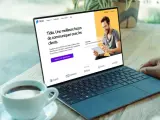 Un homme souriant utilise un logiciel de chat gratuit sur une tablette, montrant une interface de communication client sur un ordinateur portable.
