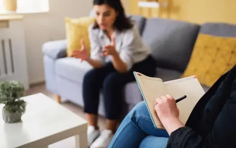 Une thérapeute prend des notes pendant une séance. Ce visuel est idéal pour un **site internet thérapeute**.