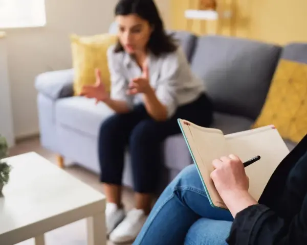 Une thérapeute prend des notes pendant une séance. Ce visuel est idéal pour un **site internet thérapeute**.